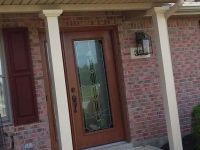 A brick house with a wooden door and a porch.