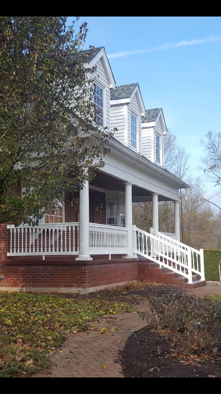A large white house with a large porch and stairs.