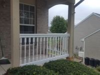 There is a porch with a white railing and a window.