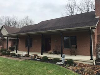 A large brick house with a porch and rocking chairs on it.