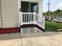 A white porch with stairs leading up to it and a white railing.