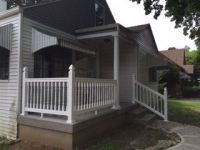 A white house with a porch and a white railing.