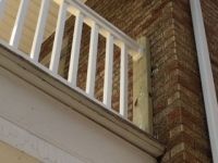 A white railing is attached to the side of a brick building.