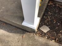A white post is sitting on top of a concrete sidewalk.