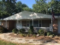 A brick house with a large porch and a flag on the roof.