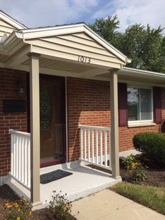 A brick house with a porch and a white railing.
