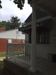 The front porch of a house with a white railing
