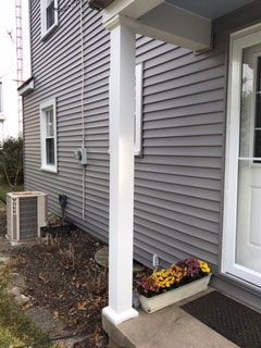 A house with a porch and a planter of flowers in front of it.