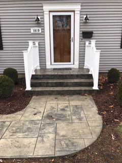 A concrete walkway leading to the front door of a house.