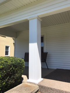 A white fence is in front of a white house.