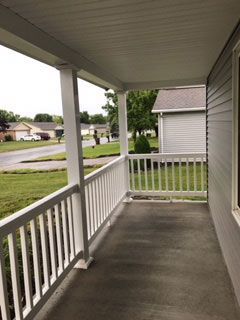There is a porch with a white railing and a window.
