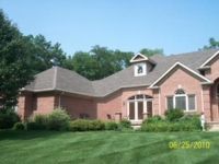 A large brick house with a large lawn in front of it.