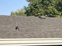 A roof with a chimney on it and trees in the background.