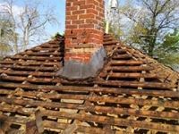A brick chimney is sitting on top of a wooden roof.