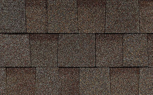 A close up of a row of brown shingles on a roof.