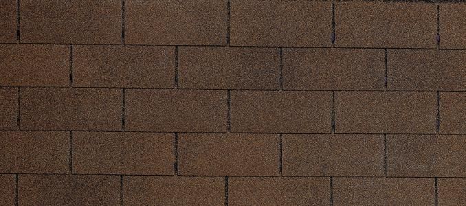 A close up of a row of brown shingles on a roof.
