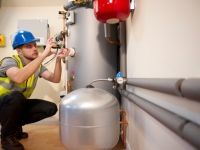 A man is working on a water heater in a room.