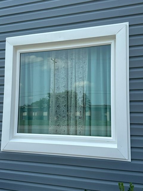 A window on the side of a house with a white frame