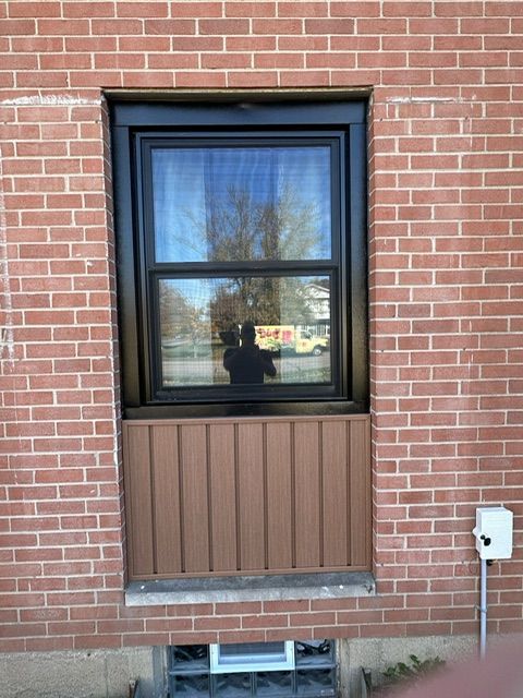 A brick building with a black window and brown siding