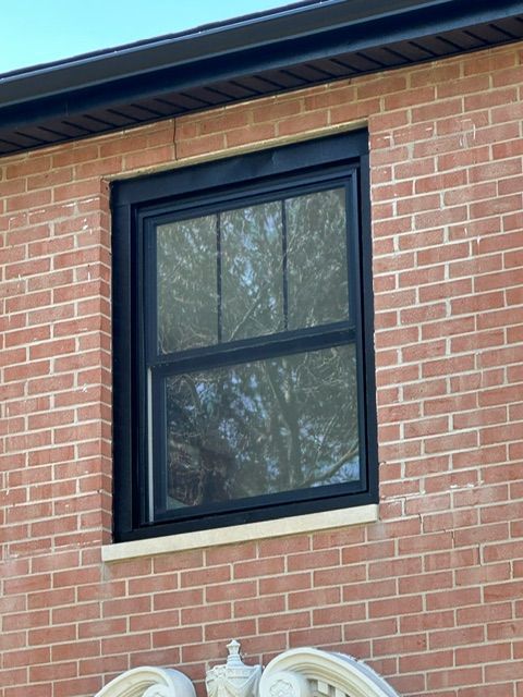 A brick building with a black window on it
