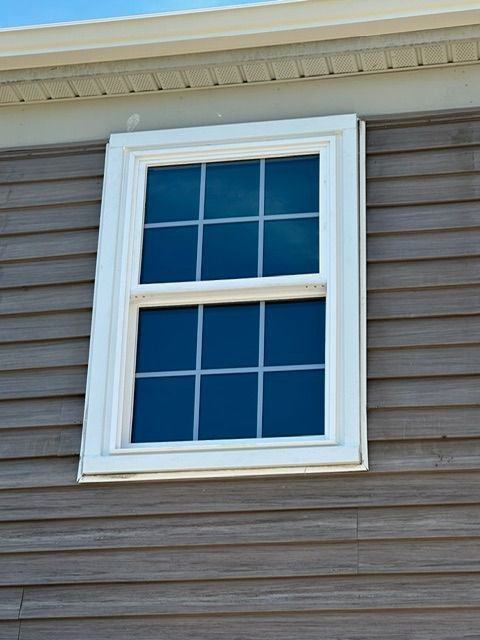 A window on the side of a house with a white frame