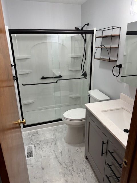 A bathroom with a toilet , sink and shower.