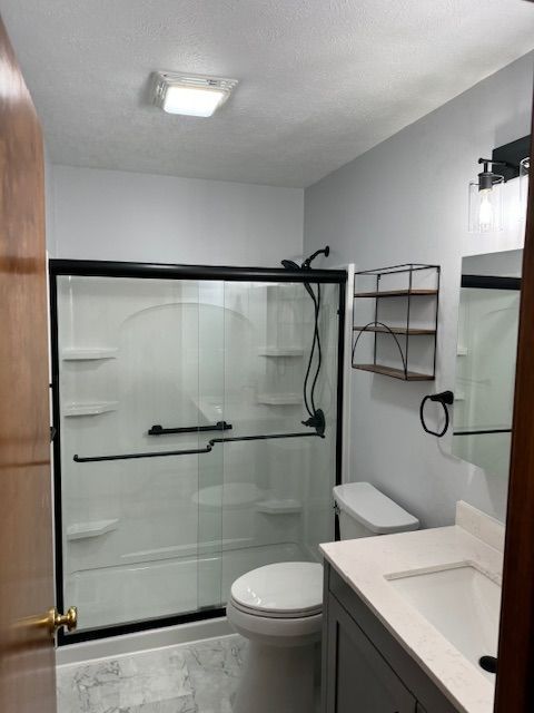 A bathroom with a toilet , sink and shower stall