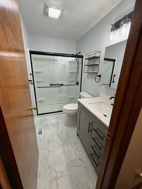 A bathroom with a toilet , sink , shower and mirror.