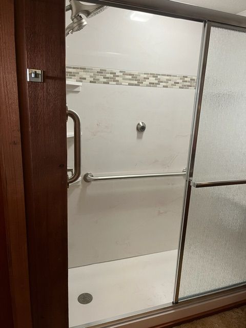 A bathroom with a walk in shower with sliding glass doors.