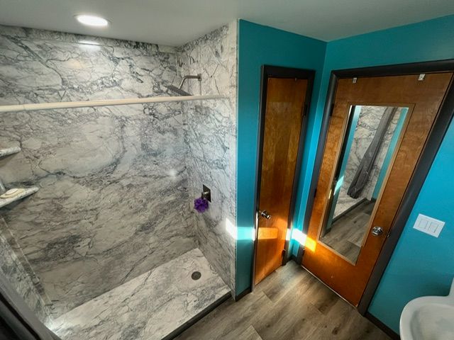 A bathroom with a walk in shower and a mirror.