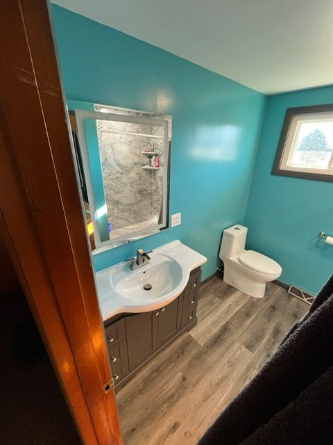 A bathroom with a sink , toilet , mirror and blue walls.
