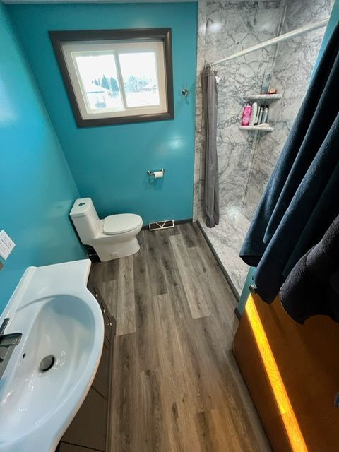 A bathroom with a toilet a sink and a shower