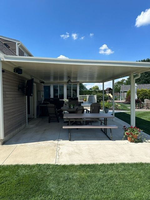 A covered patio with a picnic table and chairs