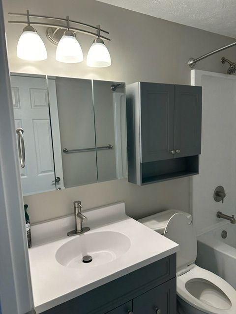 A bathroom with a sink toilet and mirror