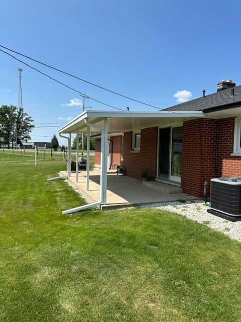 A brick house with a covered porch and a lawn in front of it.