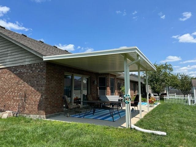 A patio with a table and chairs under a covered patio cover.