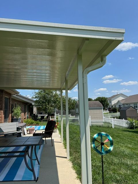 A patio with a table and chairs under a covered porch.