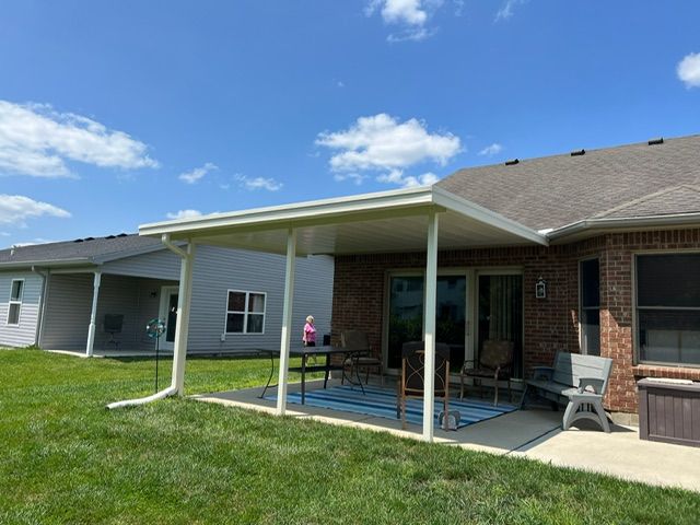 A patio with a table and chairs under a covered patio cover.