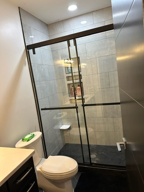 A bathroom with a toilet and a sliding glass shower door