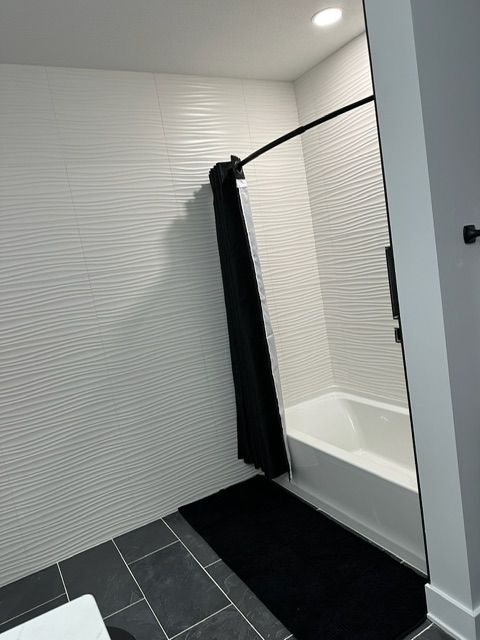 A bathroom with a white tub and a black shower curtain