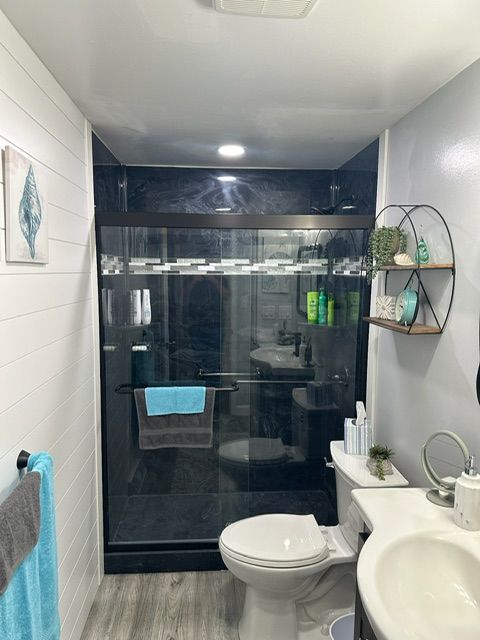 A bathroom with a toilet , sink , and shower.