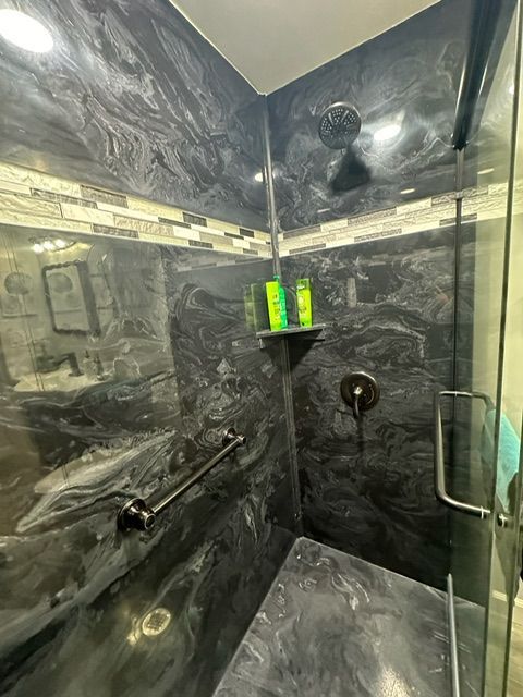 A bathroom with a walk in shower and a glass door.