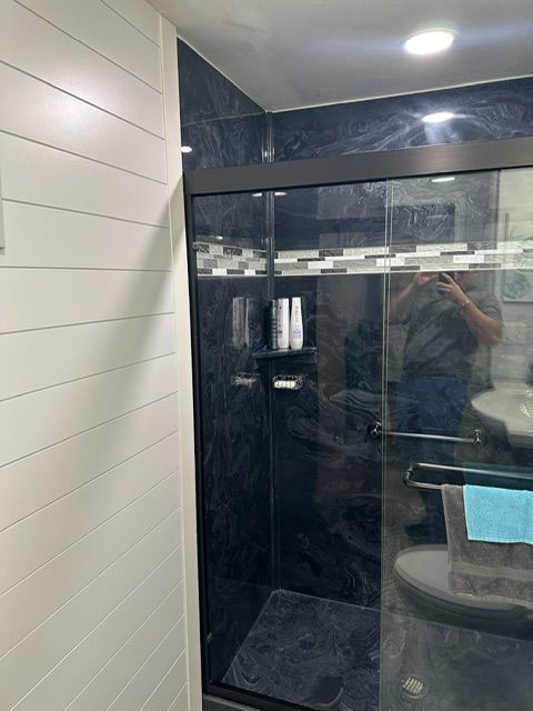A bathroom with a sliding glass shower door and a toilet.