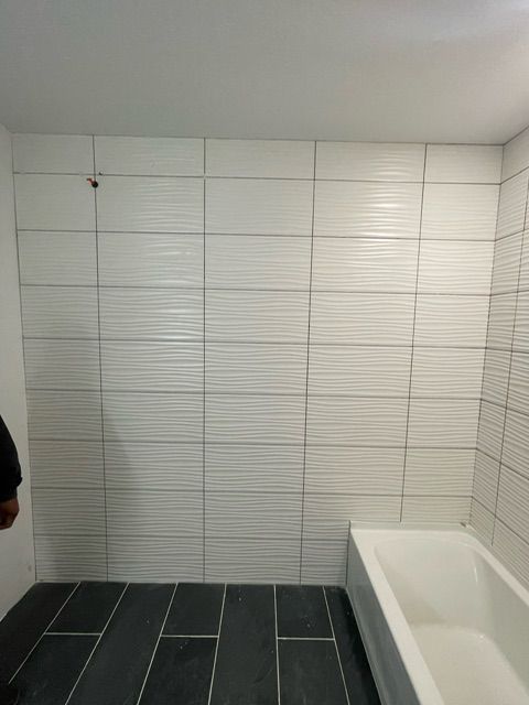 A bathroom with white tiles and a bathtub.