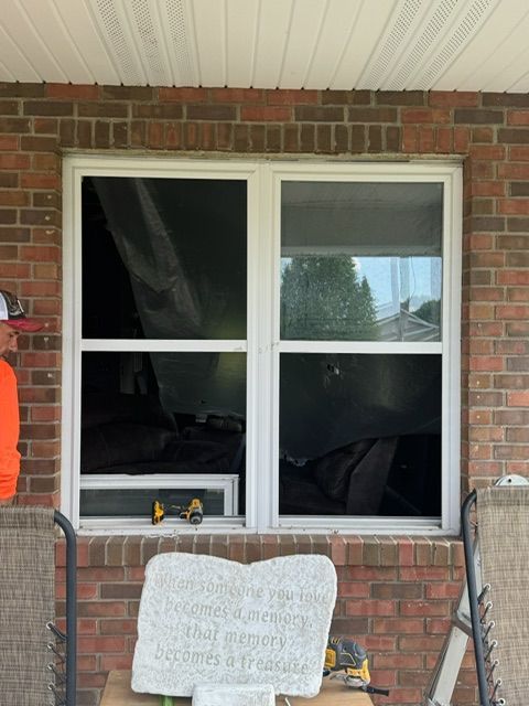 A man is working on a window on a brick house