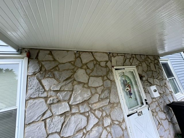 A stone wall with a white door and a white porch.