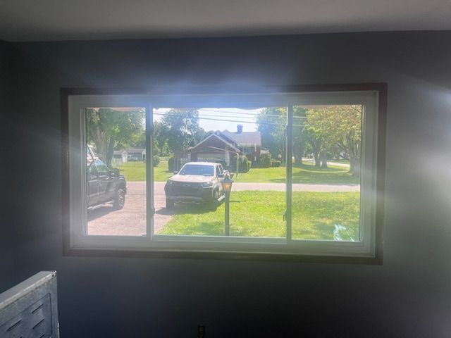 A car is parked in a driveway in front of a house through a window.