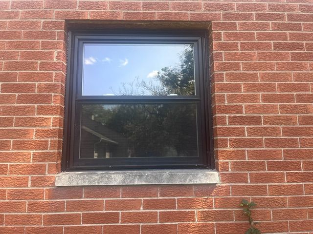 A window on a brick wall with a black frame.