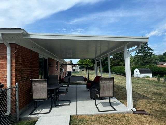 A patio with a table and chairs under a covered porch.