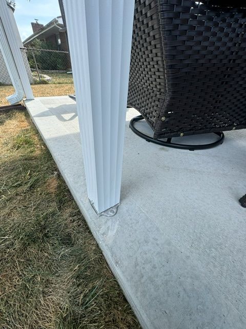 A wicker chair is sitting on a concrete patio next to a white pole.